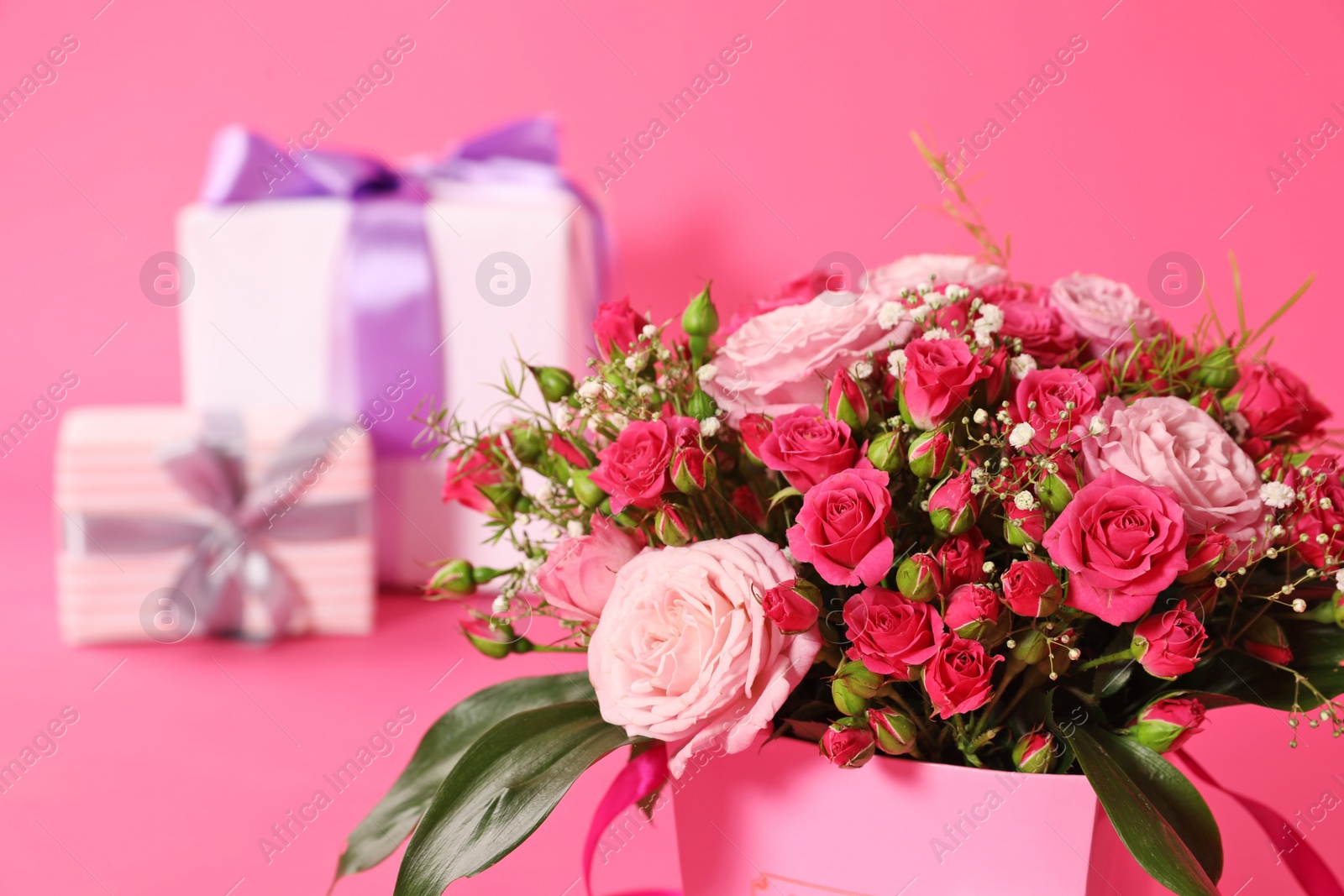 Photo of Beautiful bouquet of flowers and blurred gift boxes on background