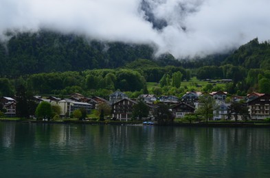 Photo of Picturesque view of beautiful village on lake shore near mountains