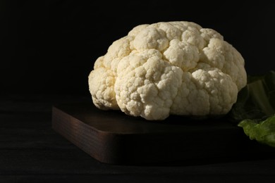 Photo of Fresh raw cauliflower on black wooden table, closeup