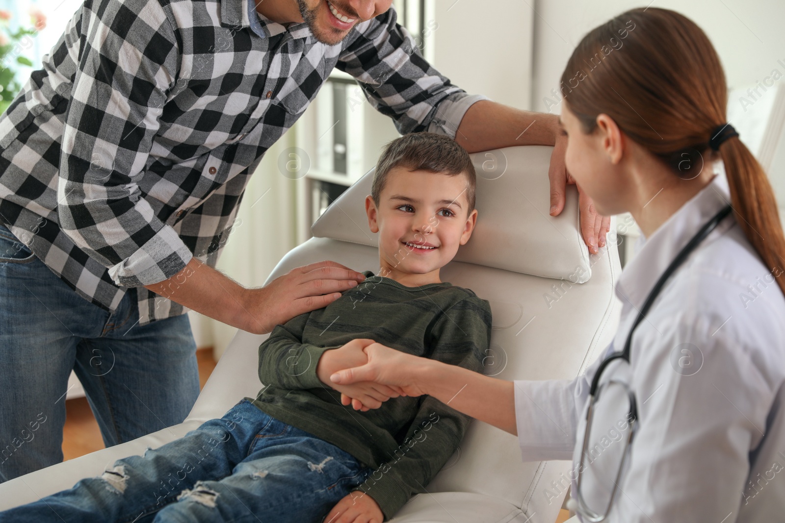 Photo of Father and son visiting pediatrician. Doctor working with patient in hospital