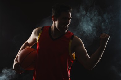 Photo of Basketball player with ball on black background