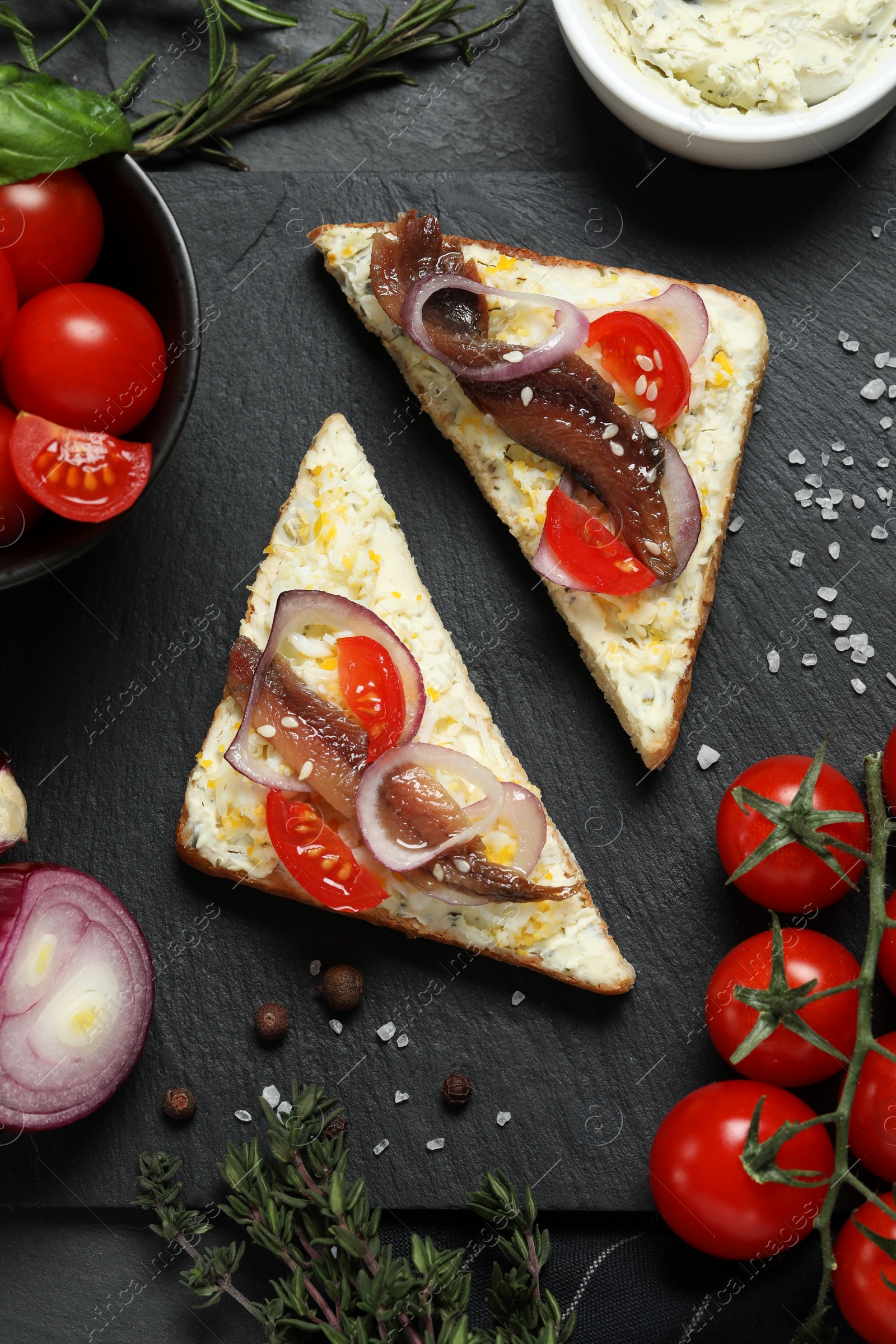 Photo of Flat lay composition with delicious anchovy sandwiches on black table