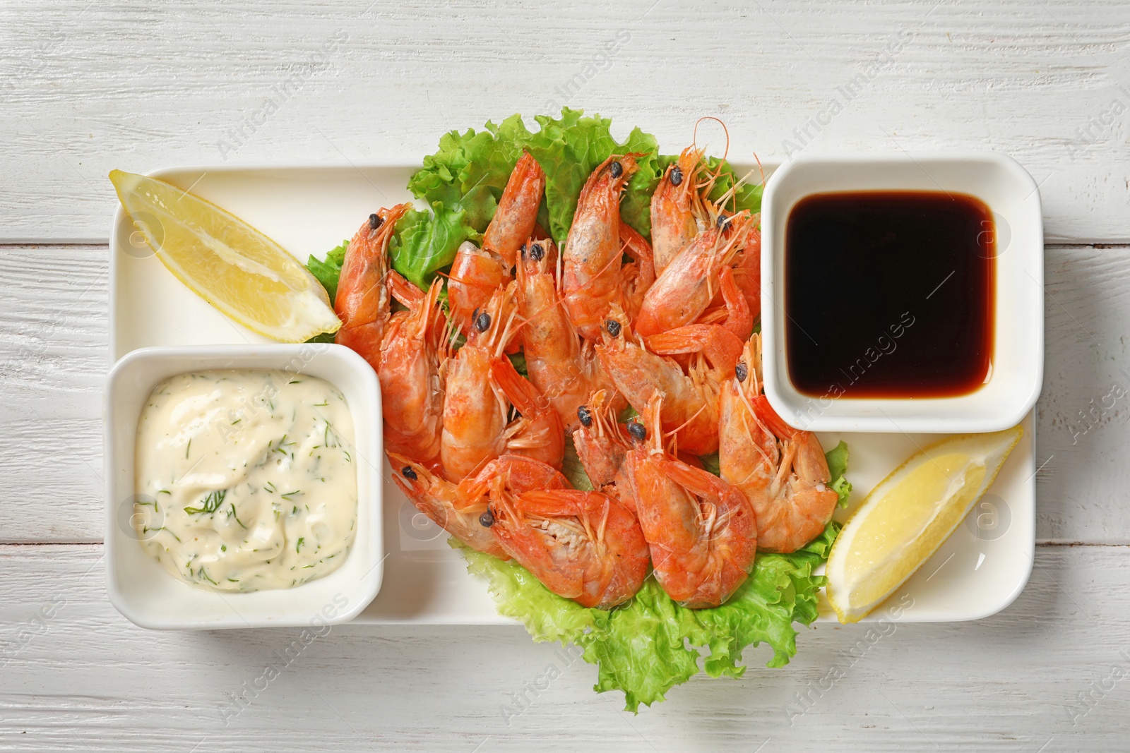 Photo of Plate with juicy shrimps and sauces on table, top view