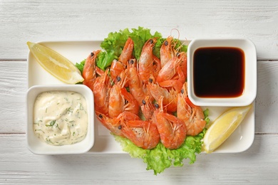 Photo of Plate with juicy shrimps and sauces on table, top view