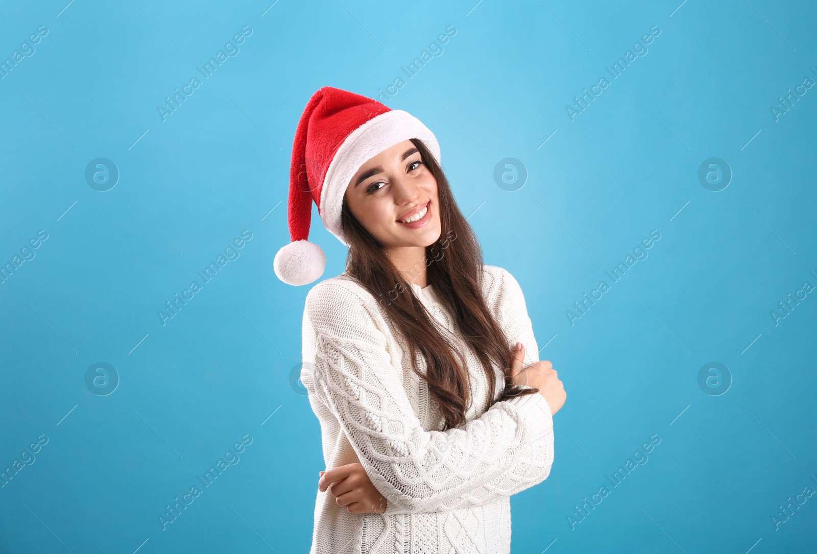 Photo of Beautiful woman wearing Santa Claus hat on light blue background