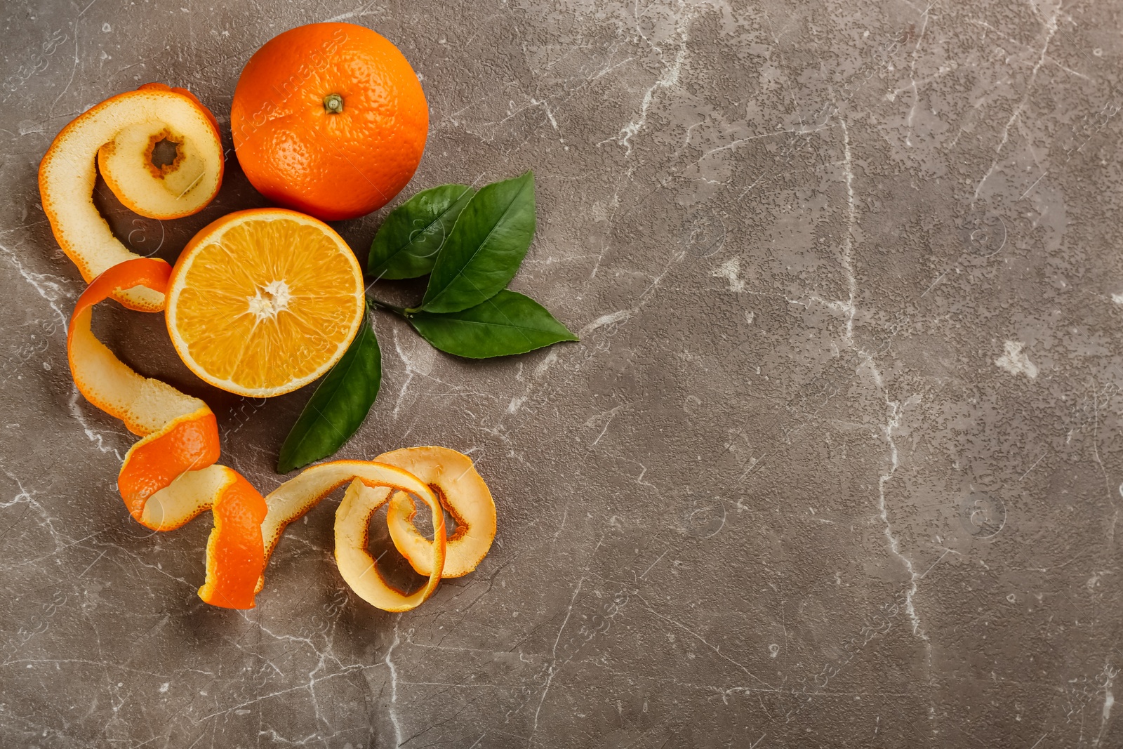 Photo of Orange fruits with peel on grey marble table, flat lay. Space for text