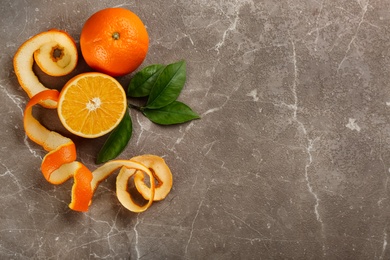 Orange fruits with peel on grey marble table, flat lay. Space for text