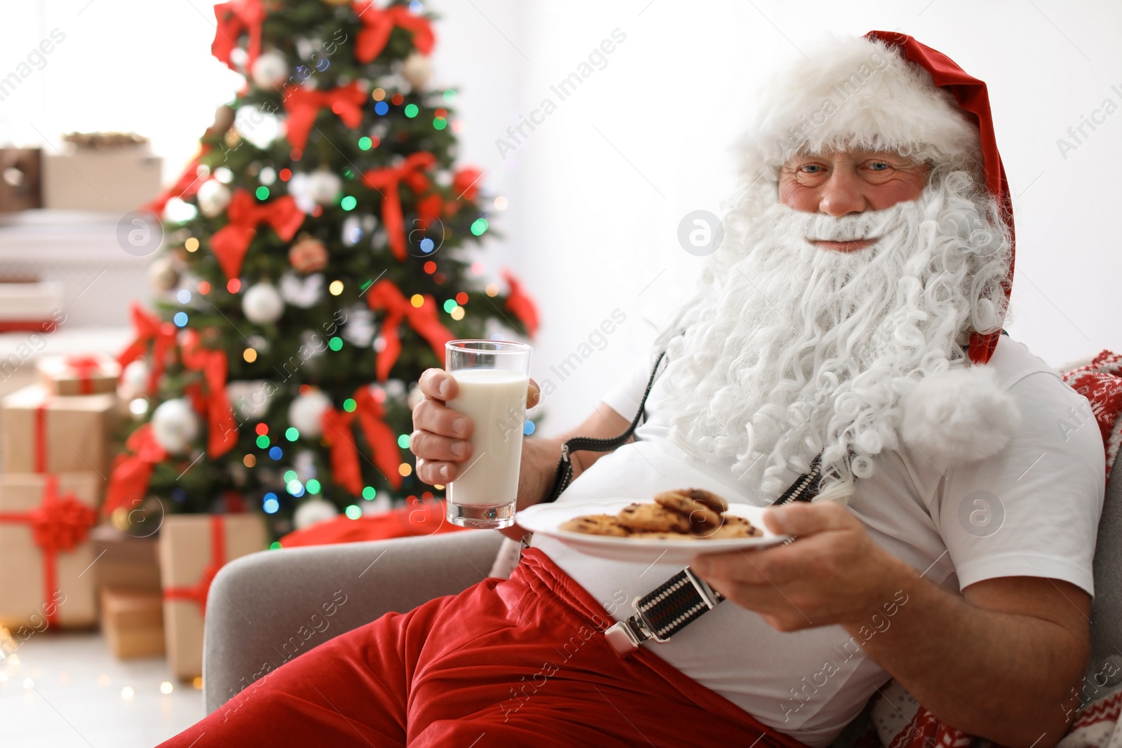 Photo of Authentic Santa Claus with milk and cookies indoors