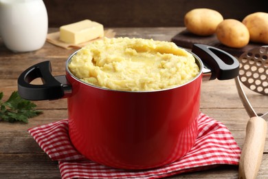 Red pot with tasty mashed potatoes on wooden table