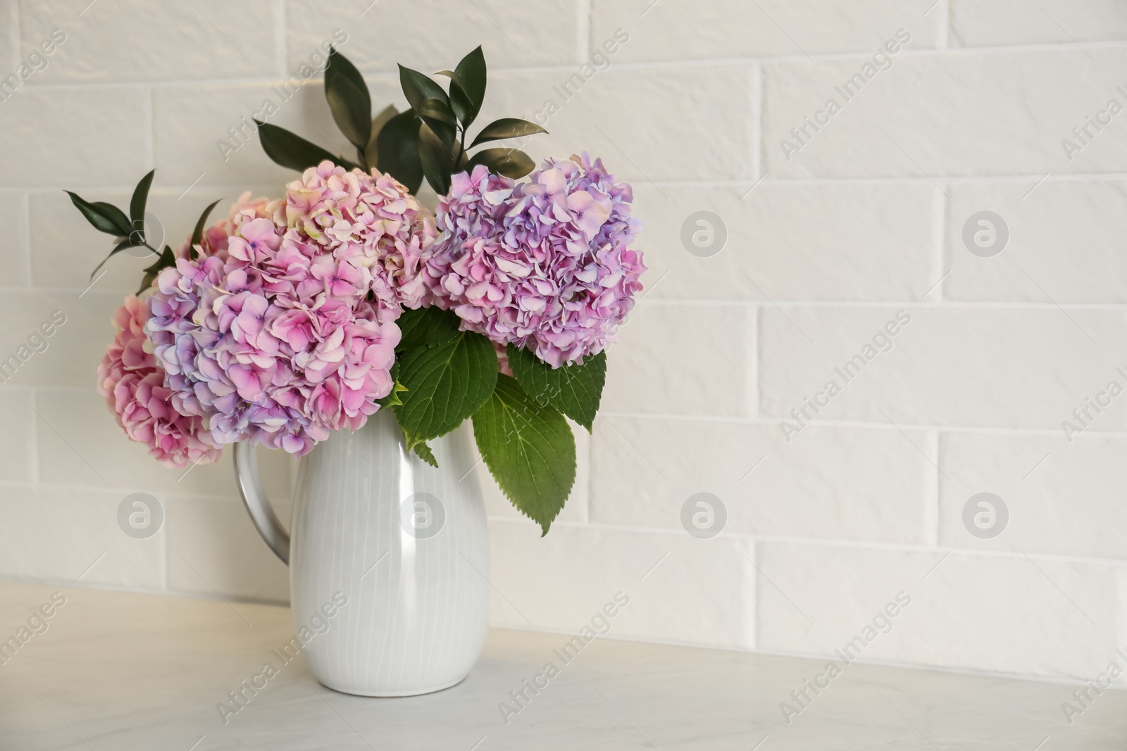 Photo of Bouquet with beautiful purple hydrangea flowers on light countertop. Space for text