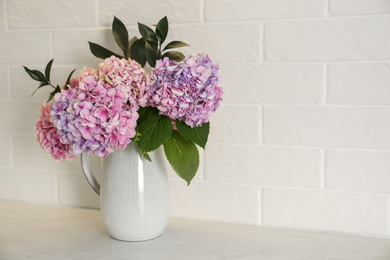 Bouquet with beautiful purple hydrangea flowers on light countertop. Space for text