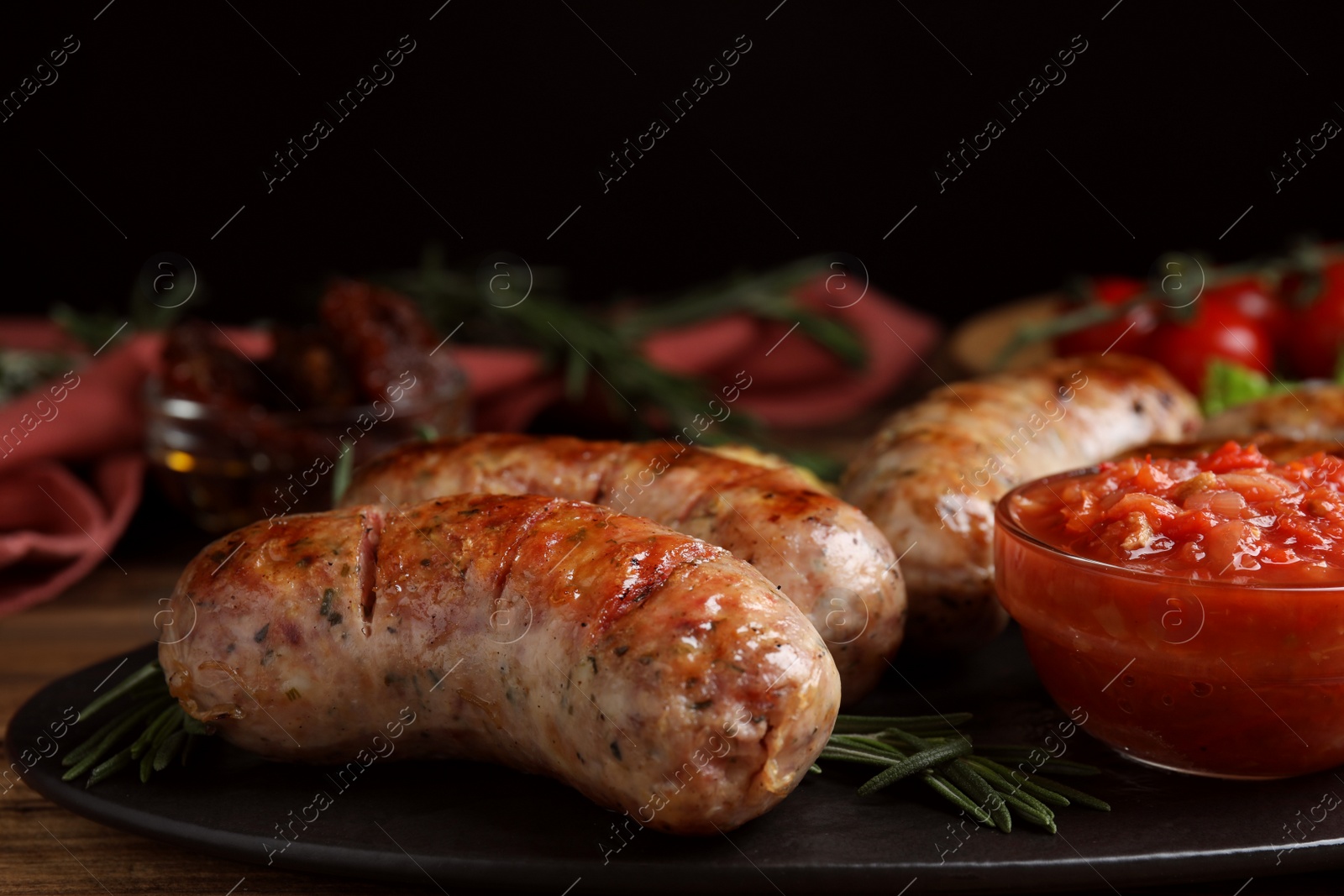 Photo of Tasty grilled sausages served with sauce on wooden table