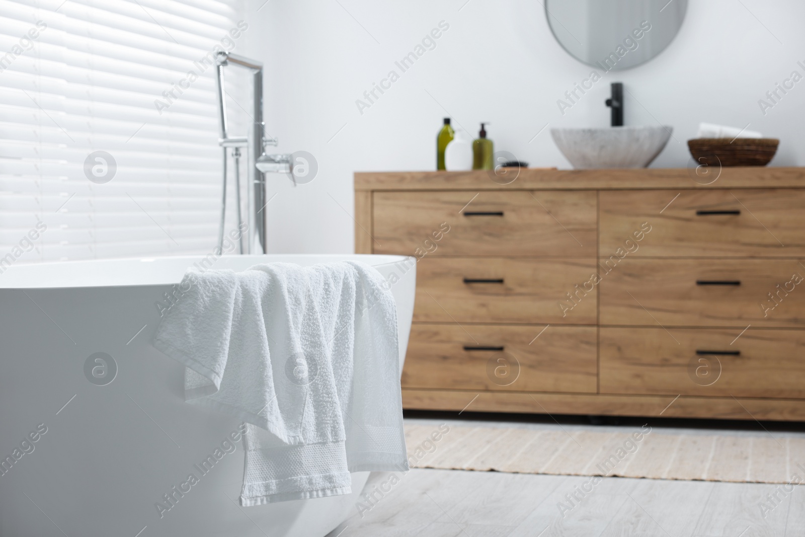 Photo of Soft bath towel on tub in bathroom. Space for text