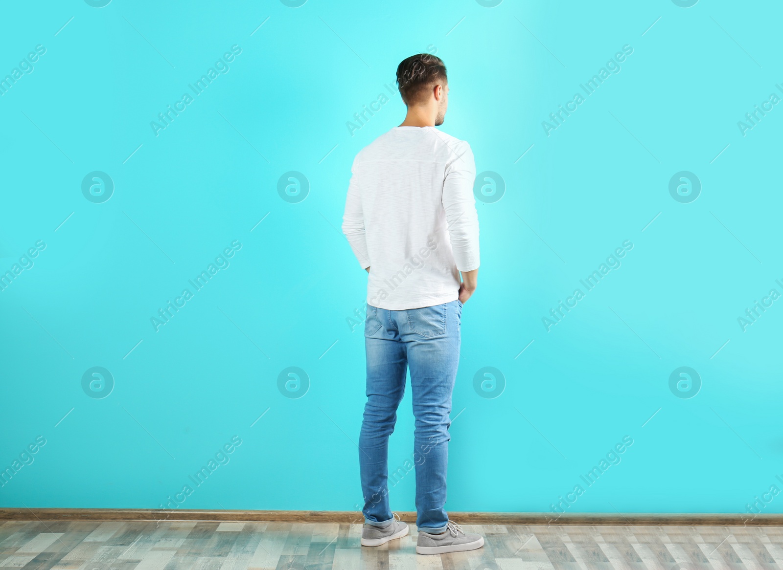 Photo of Young man in stylish jeans near color wall