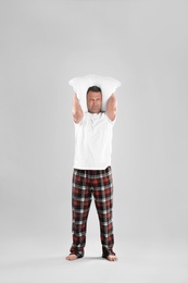 Man holding soft pillow on light background