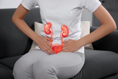 Woman suffering from cystitis on sofa at home, closeup. Illustration of urinary system