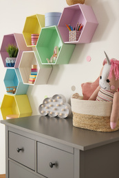 Photo of Bright colorful shelves on light wall in room. Interior design