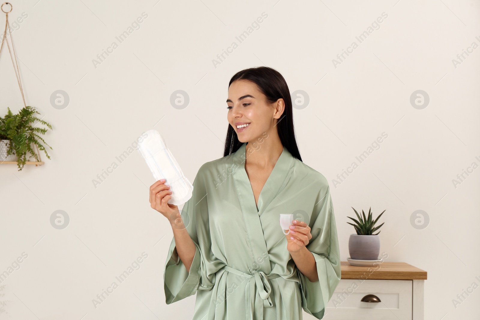 Photo of Young woman with menstrual cup and pad at home