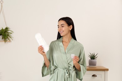 Young woman with menstrual cup and pad at home