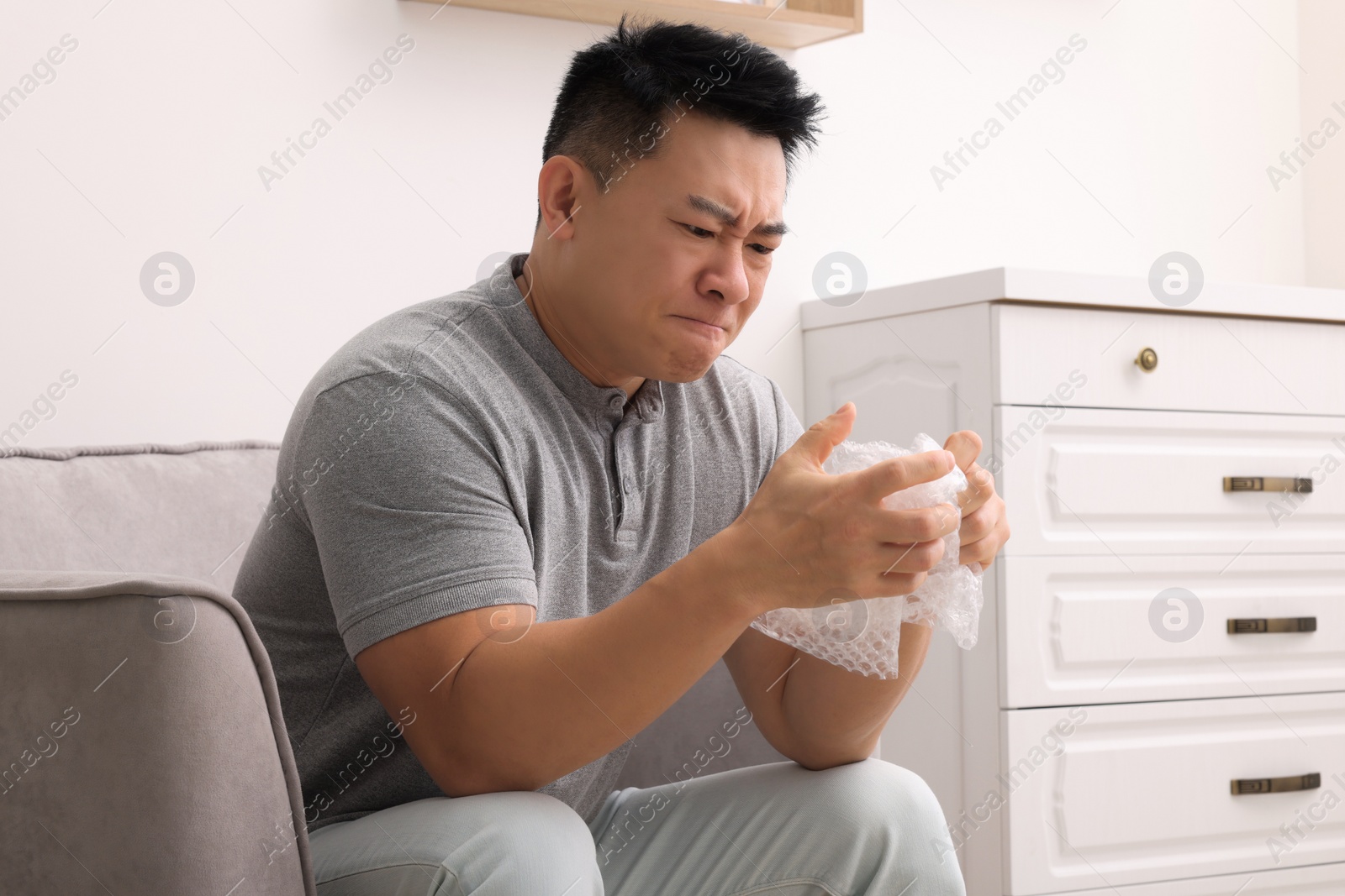 Photo of Emotional asian man with bubble wrap indoors