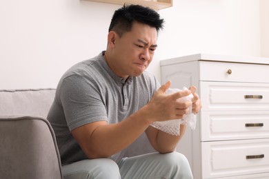 Emotional asian man with bubble wrap indoors