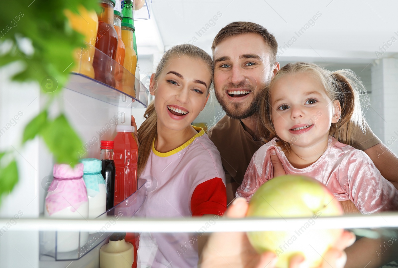 Photo of Happy family looking into refrigerator and choosing products in kitchen