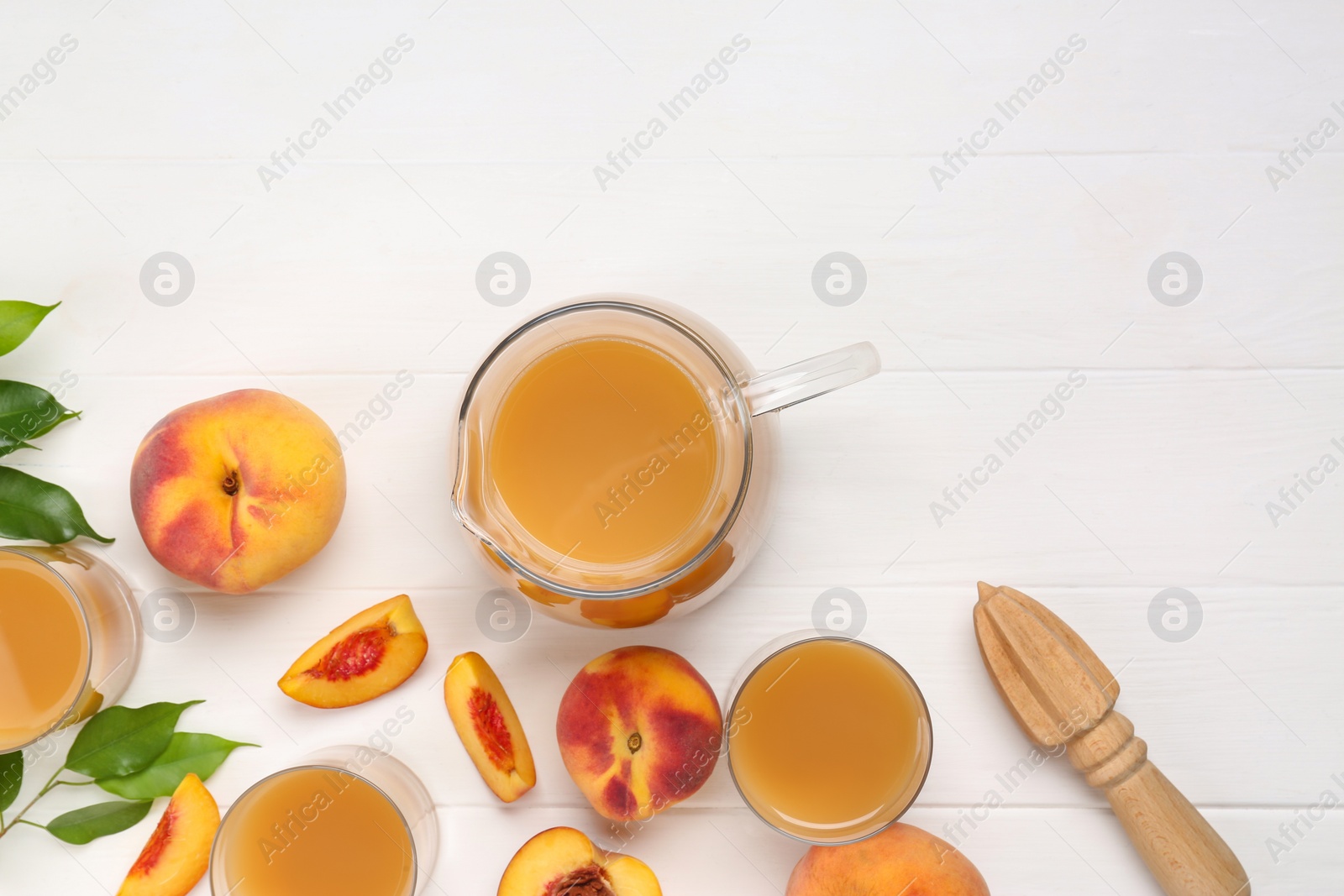 Photo of Delicious peach juice, fresh fruits and leaves on white wooden table, flat lay. Space for text