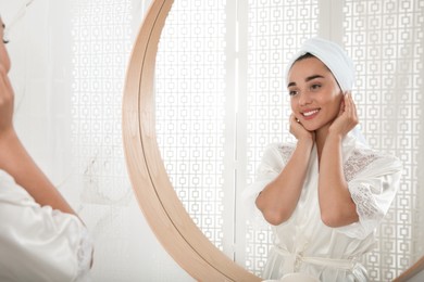 Beautiful young woman with perfect skin near mirror in bathroom. Facial wash