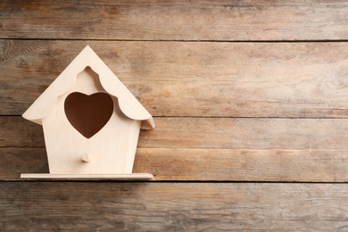 Photo of Beautiful bird house with heart shaped hole on wooden background, space for text