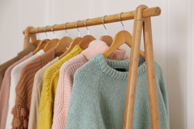 Different stylish warm clothes on rack indoors
