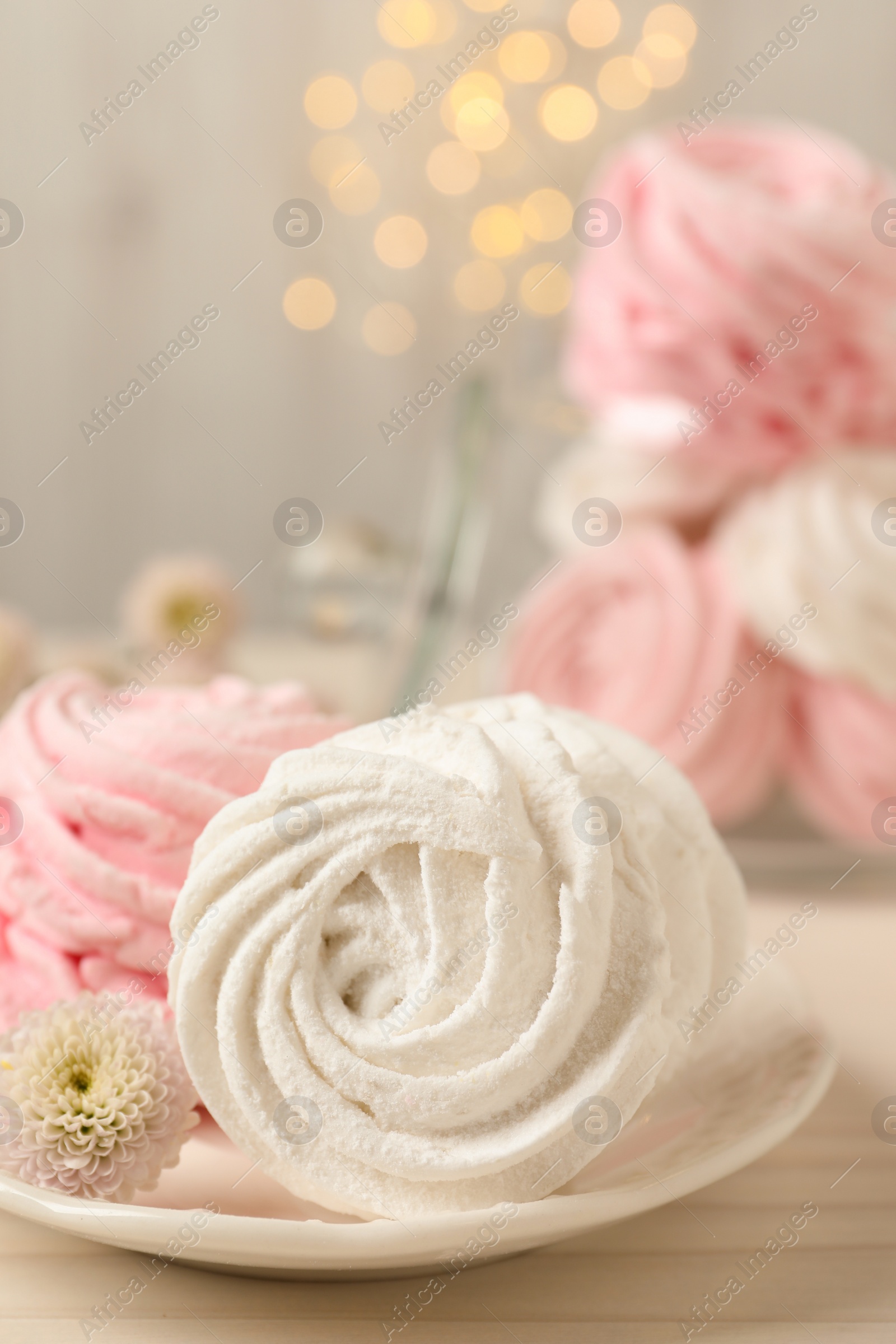 Photo of Delicious marshmallows on wooden table against blurred lights, closeup