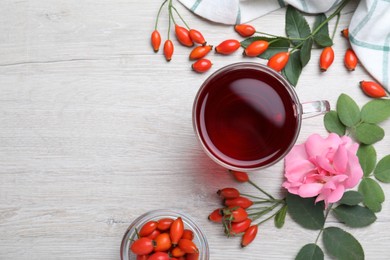 Flat lay composition with aromatic rose hip tea on white wooden table. Space for text