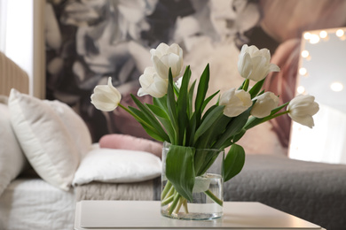 Vase with white tulips on table in bedroom. Interior element
