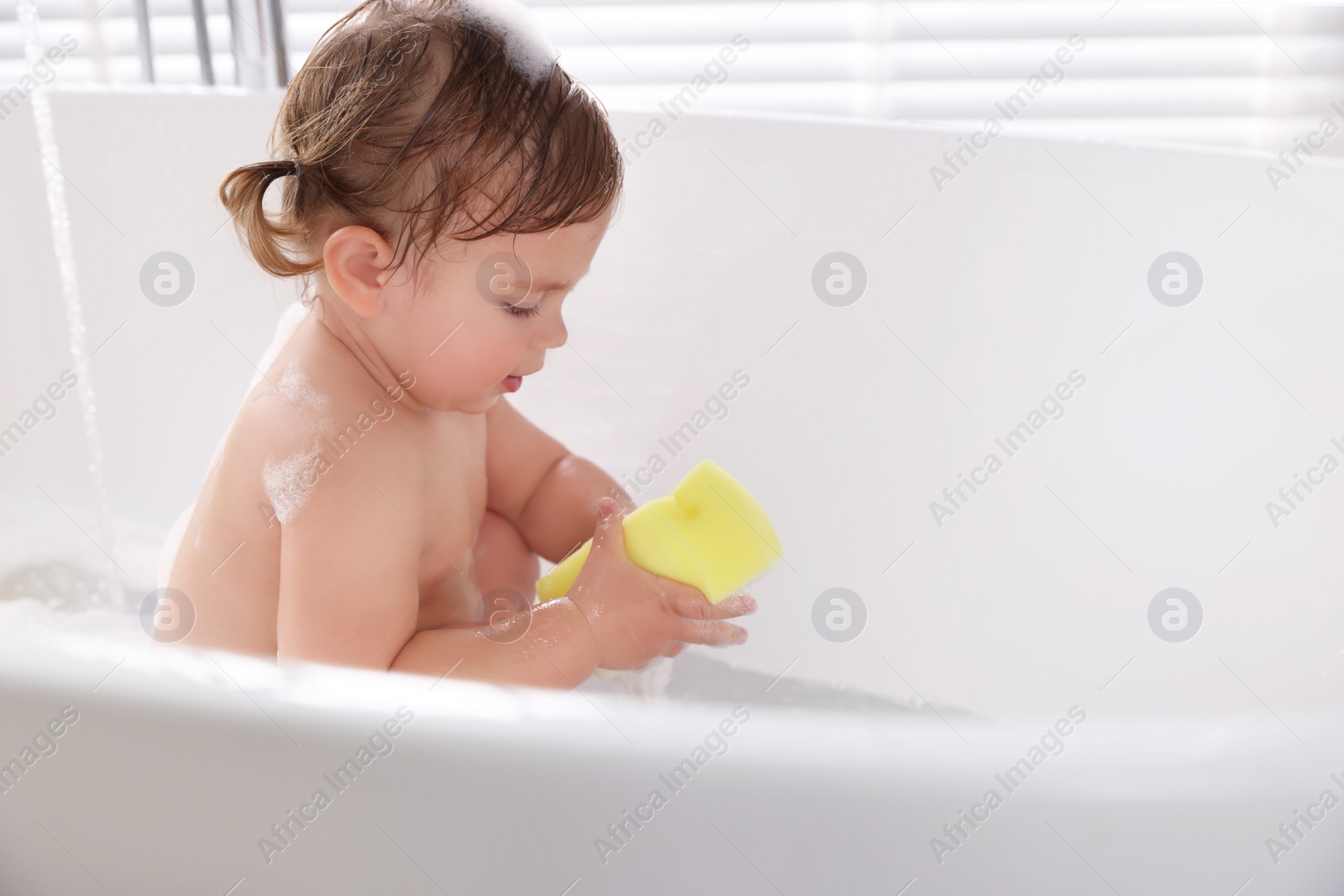 Photo of Cute little girl with bast wisp taking bubble bath. Space for text