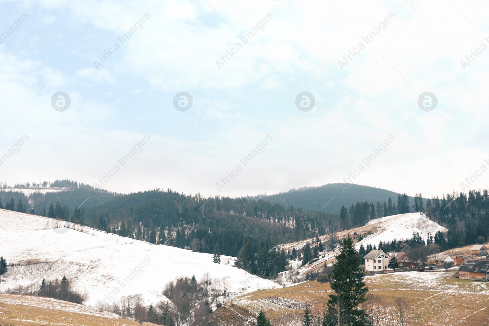 Photo of Beautiful winter landscape with buildings and forest on snowy hills