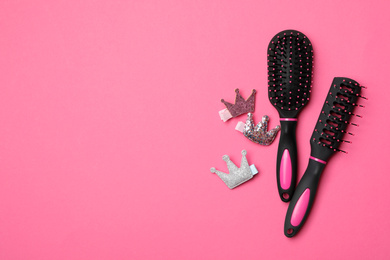 Flat lay composition with modern hair brushes on pink background, space for text