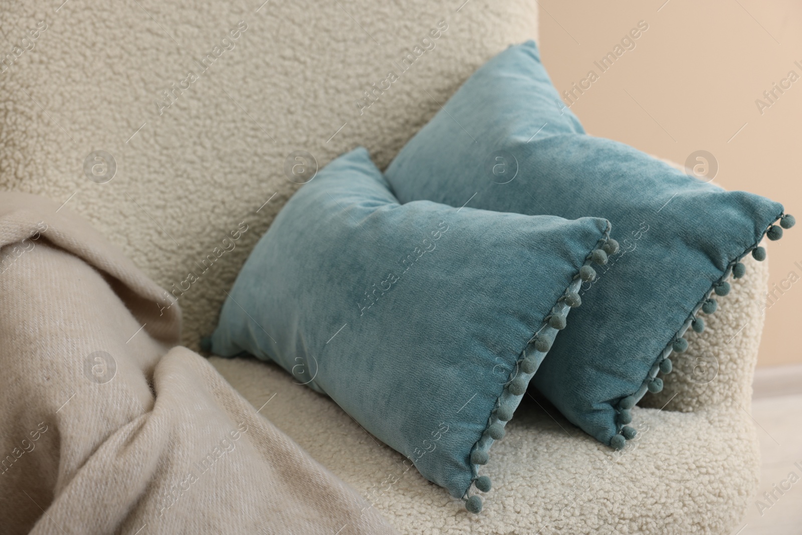 Photo of Soft blue pillows and blanket on armchair indoors