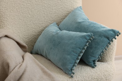 Soft blue pillows and blanket on armchair indoors