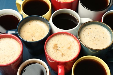 Photo of Many cups of different coffee drinks on blue table