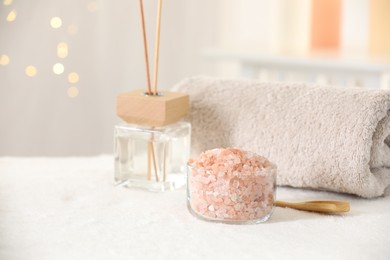 Photo of Spa composition. Sea salt, towel and reed air freshener on soft white surface, space for text
