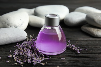 Photo of Natural herbal oil and lavender flowers on wooden background