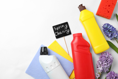 Photo of Composition with Spring Cleaning sign, flowers and detergents on white background, top view