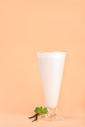 Photo of Glass with vanilla milk shake on color background