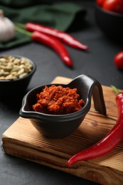 Photo of Dish with red curry paste and ingredients on black table, closeup