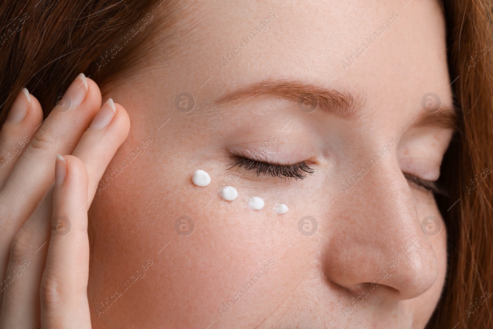 Photo of Beautiful woman with freckles and cream on her face, closeup