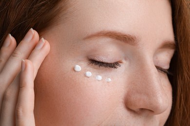 Photo of Beautiful woman with freckles and cream on her face, closeup