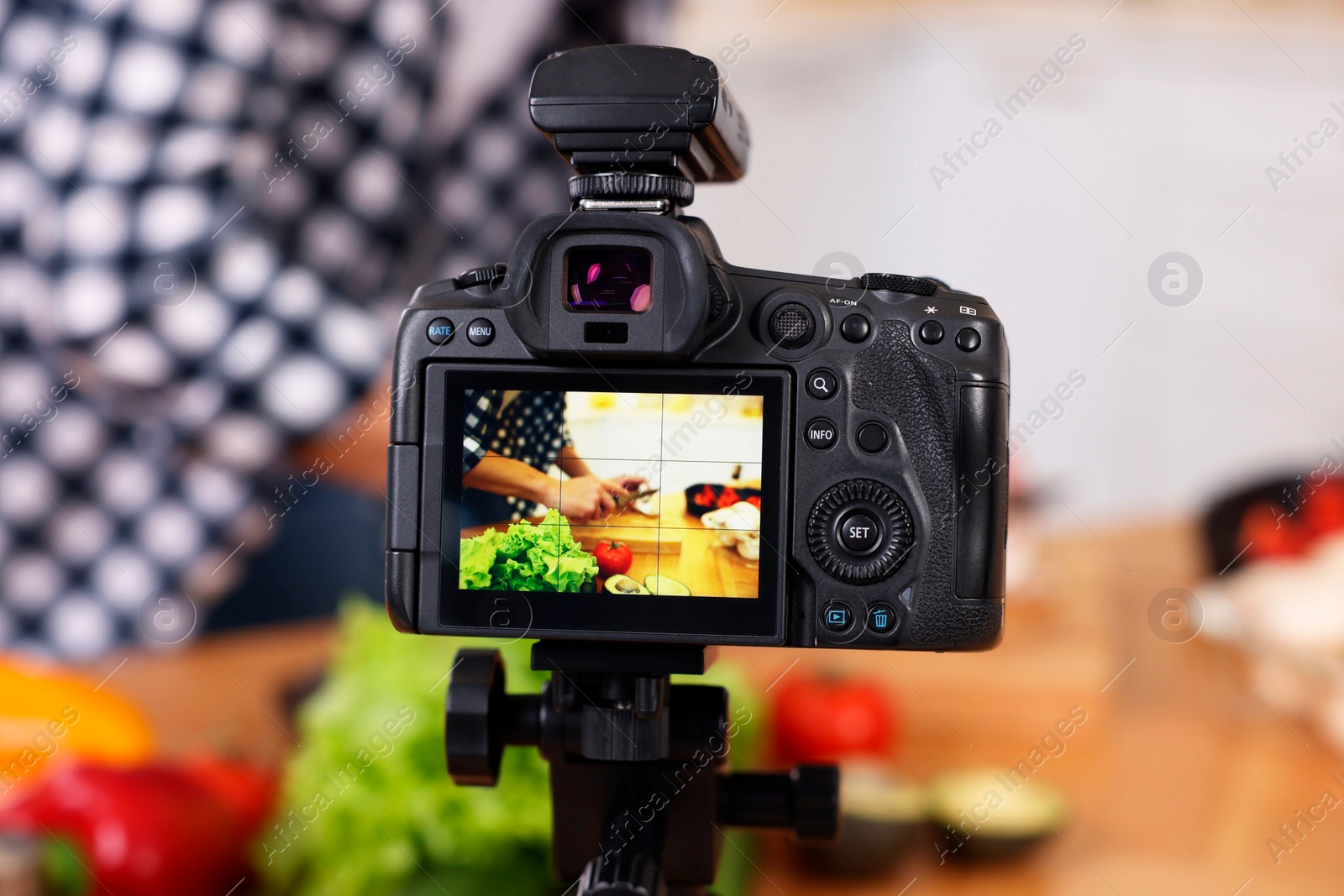 Photo of Food blogger cooking while recording video in kitchen, focus on camera