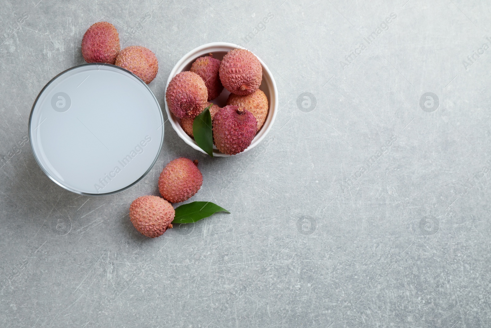 Photo of Lychee juice and fresh fruits on light background, flat lay. Space for text