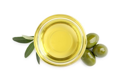 Photo of Glass bowl of oil, ripe olives and green leaves on white background, top view