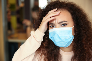 African-American woman with disposable mask in cafe. Virus protection